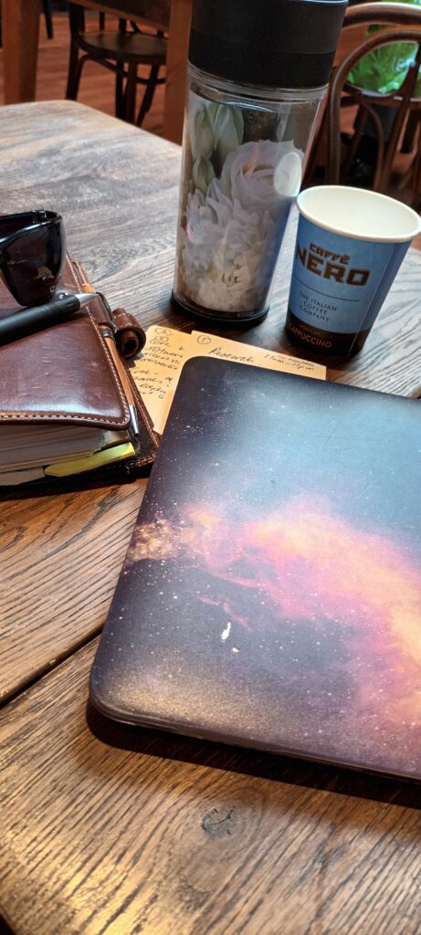 Laptop and portfolio with freshly brewed coffee on a solid wood table that has character and charm. Work life balance.